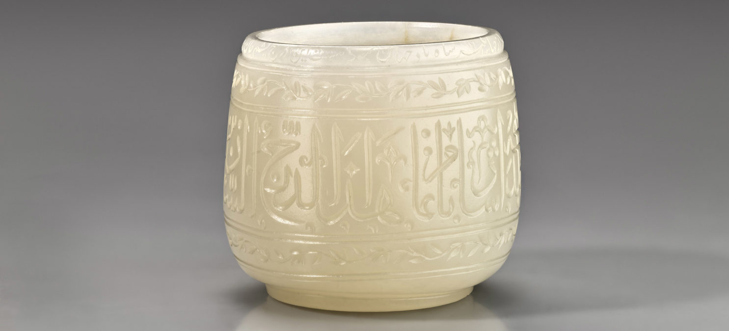 Detailed view of a white jade cup with calligraphic inscriptions around the body