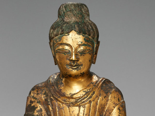 Face and shoulders of a golden Buddha statue.