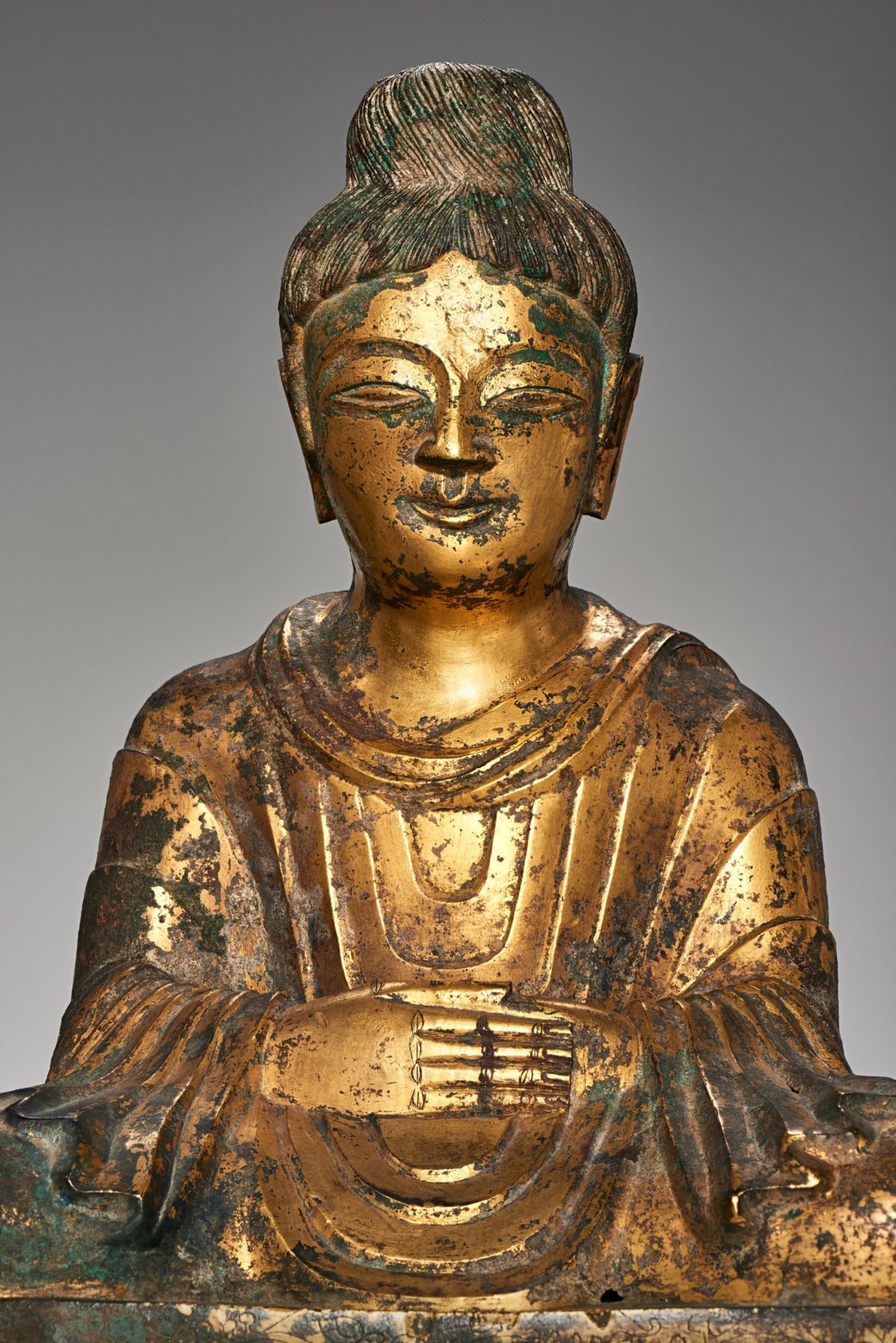 Face and shoulders, and body of a golden Buddha statue.