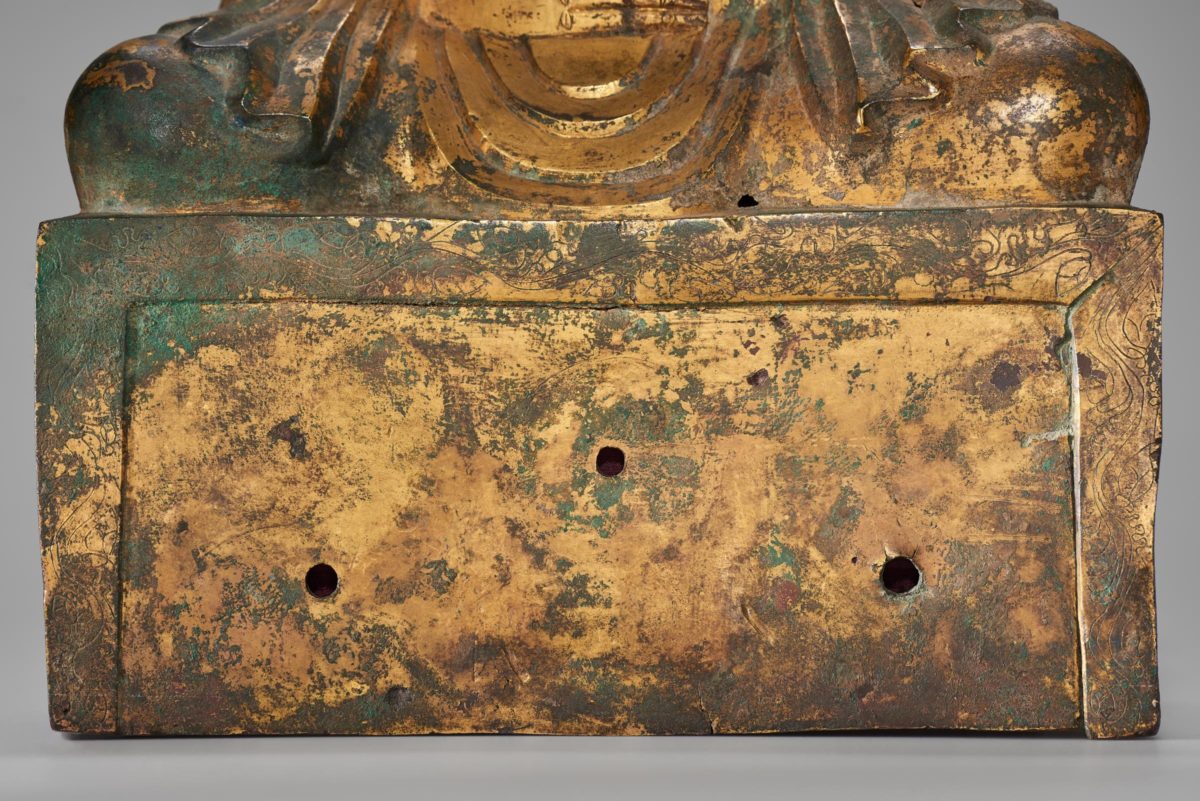 View of the base of a golden Buddha statue with three small holes.